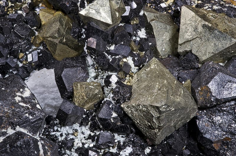Kristal magnetit gelap mengelilingi kristal pirit yang lebih terang pada spesimen dari Brosso.